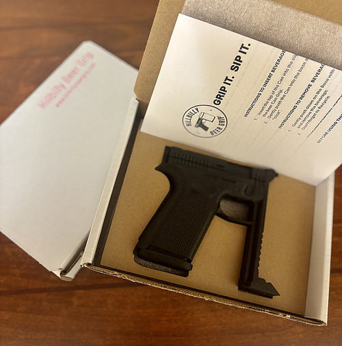 Black gun grip in a cardboard box with branding and text on a wooden surface
